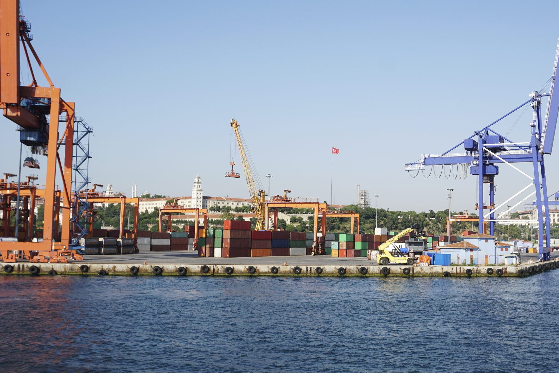 Container port quayside with orange and blue gantry cranes and stacked shipping containers