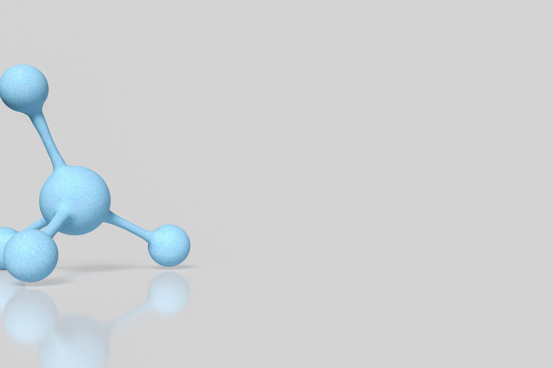 Pale blue ball-and-stick molecular model on a light grey reflective surface
