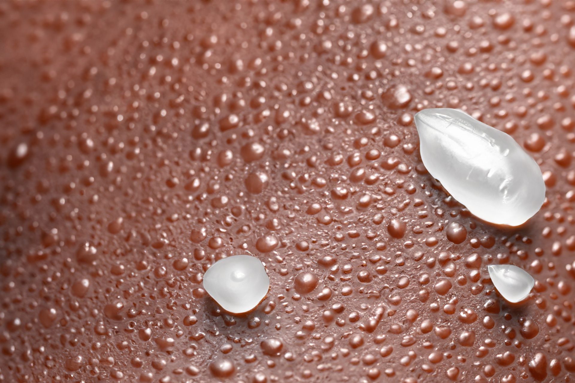 Gotas de gel transparente y pequeñas gotas de agua sobre piel morena, en primer plano
